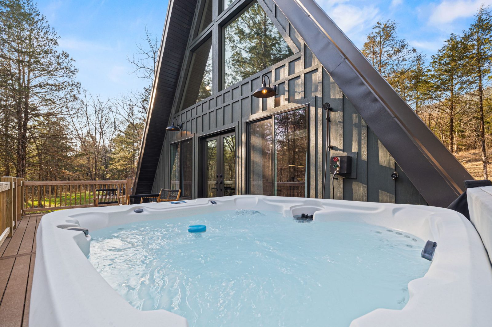 The hot tub on the deck with the A-frame cabin behind