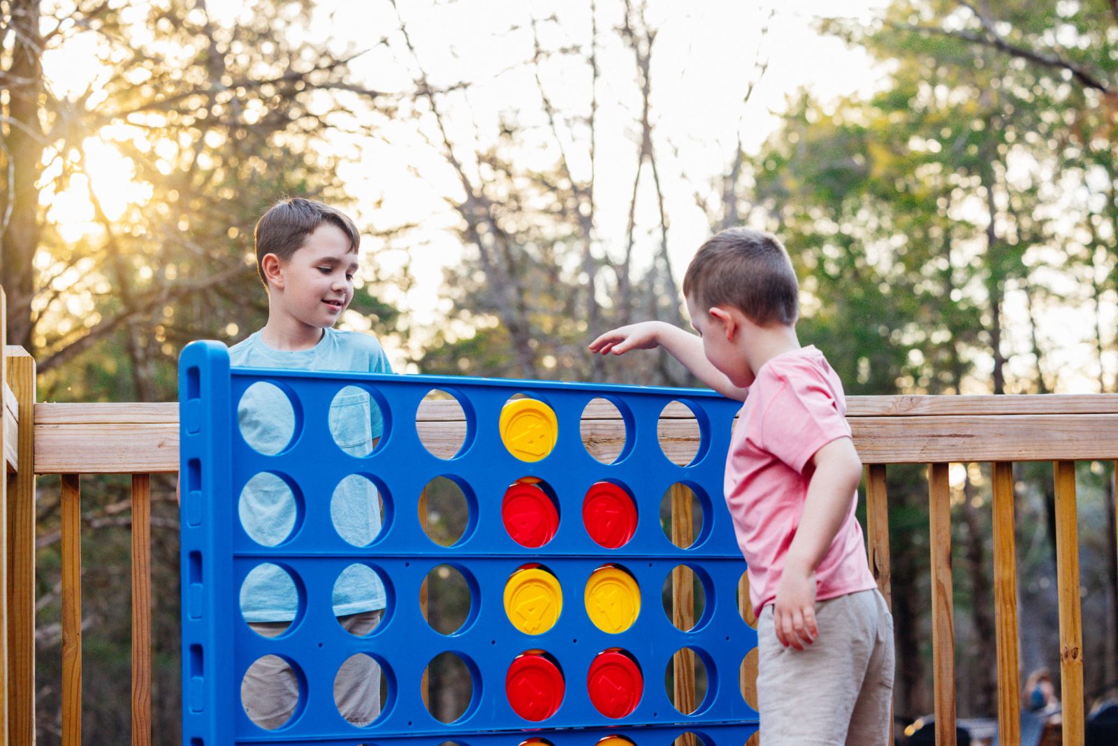 Kids playing giant Connect Four on the deck at sunset