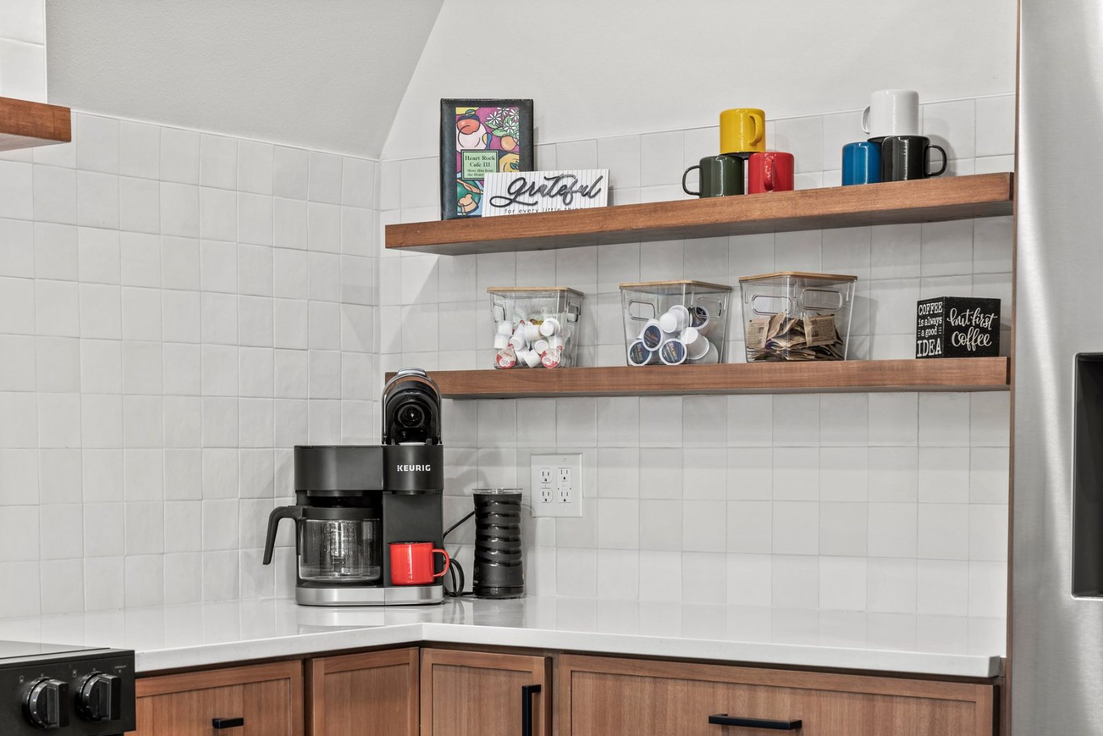 The coffee bar with Keurig and shelves stocked with coffee pods, mugs, and tea