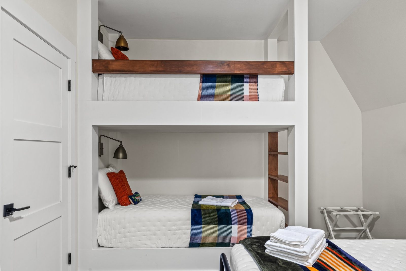 The built-in bunk beds with brass reading lamps and plaid blankets